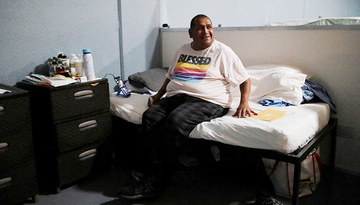 Homeless man with a smile enjoying sitting in his bed