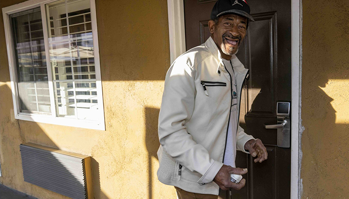 Man unlocking the door to his home while smiling.