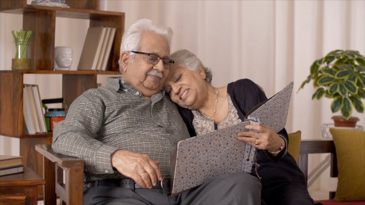 Senior couple sitting down while enjoying viewing photo album
